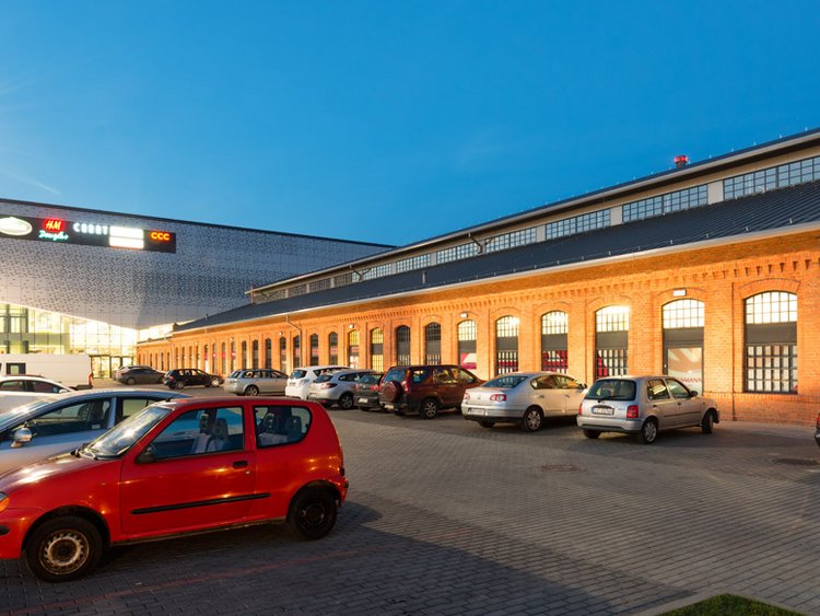 Photo: FERIO Wawer: a historic work hall with a brick façade leads to a new construction; parked cars in front