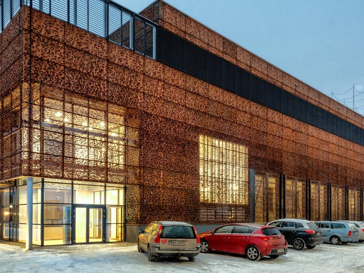 Photo: OCEAN Centre of Excellence: Corner view of the cuboid building, brightly lit from inside, with cars parked in front 