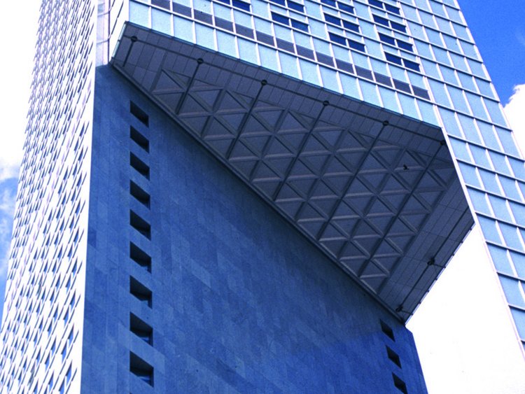 Photo: InterContinental Warszawa: View of the high-rise building from an angle below. The sky and the clouds are reflected in the glass façade.